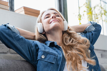 Music phone application. Relaxed happy serene mature middle-aged caucasian woman listening to the...