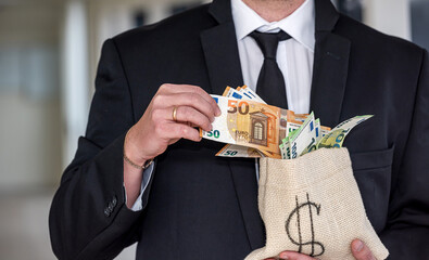 A middle-aged man in a business shirt holds a bag of dollars with an angry face.