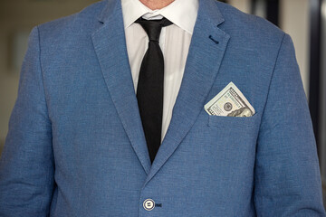 handsome young businessman in a stylish jacket from a suit with a large sum of dollars.