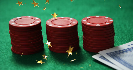 Image of gold stars falling over two three stack of casino chips and card on green background - Powered by Adobe