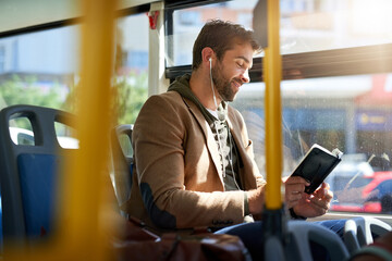Checking out the best tourist spots. Cropped shot of a handsome young man reading a book during his morning bus commute. - Powered by Adobe