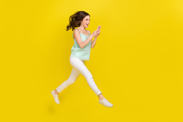 Fototapeta na wymiar Full length profile side photo of cute charming casual wear girl surfing social media isolated on yellow color background