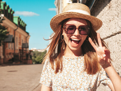 Young beautiful smiling hipster woman in trendy summer clothes. Sexy carefree woman posing on the street background at sunset. Positive model outdoors. Cheerful and happy in sunglasses and hat