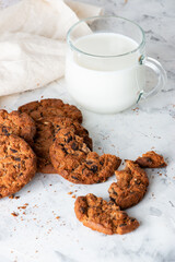 Oatmeal cookies with chocolate chips and a mug with milk on a light background. Breakfast concept.