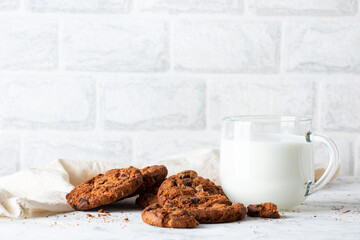 Oatmeal cookies with chocolate chips and a mug with milk on a light background. Breakfast concept.