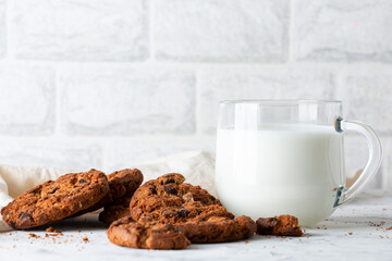 Oatmeal cookies with chocolate chips and a mug with milk on a light background. Breakfast concept.