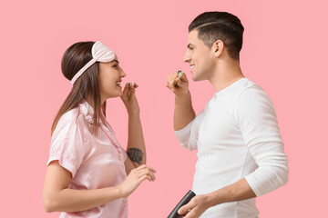 Young couple brushing teeth with activated charcoal tooth paste on pink background