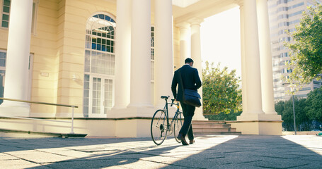 Back to the 9 to 5 hustle. Rearview shot of a businessman commuting to work with his bicycle.