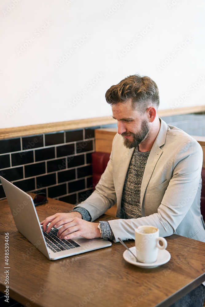 Poster working in a comfortable environment. cropped shot of a modern businessman using his laptop in a cof
