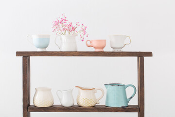pink gypsophila and cups on  wooden shelf on  white background