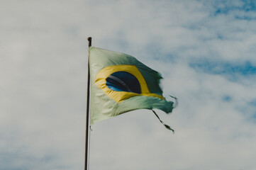 Torn Brazil flag in a blue sky