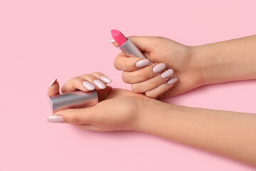 Female hands with beautiful manicure and lipstick on pink background