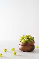Ripe sweet gooseberry in a wooden bowl on white background. Copy space for text, side view. Summer harvest of berries. Organic vegeterian food