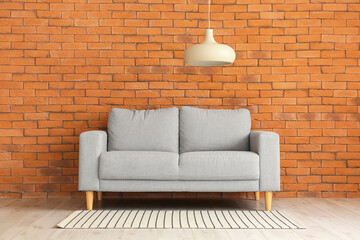 Stylish sofa near brick wall