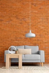 Stylish sofa and table near brick wall