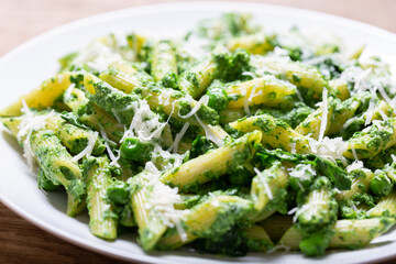 plate of pasta with spinach, peas and parmesan cheese