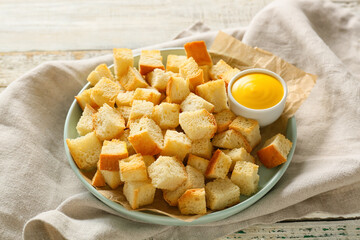 Plate of crunchy croutons and tasty sauce on wooden table