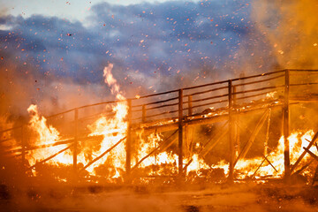 Burning wooden bridge in a raging flame close-up. Bridge on fire at dark night. Transition in...