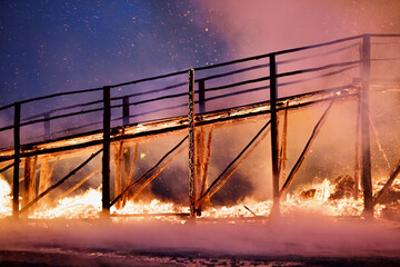 Burning wooden bridge in a raging flame close-up. Bridge on fire at dark night. Transition in...