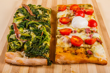 Tranci di pizza romana con scarole, acciughe, mozzarella, pomodori, pesto di basilico e mozzarella di bufala fresca