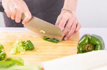Cut vegetables on a wooden chopping board with both hands