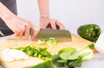 Cut vegetables on a wooden chopping board with both hands