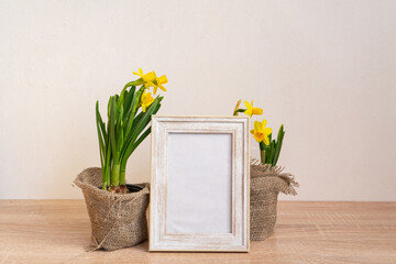 Portrait picture frame mockup with yellow daffodils in natural decorated pots.Ecofriendly life