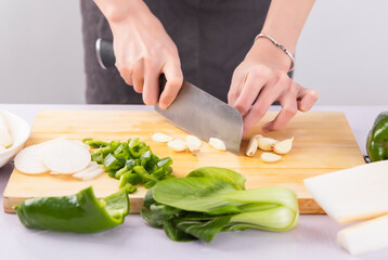 Cut vegetables on a wooden chopping board with both hands