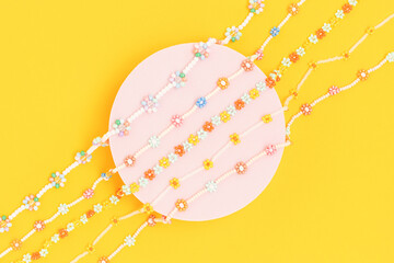 Flowers necklaces made from colorful beads on a yellow background.