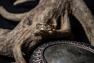 Golden ring on a wooden branch on a black background. Beautiful women's accessory