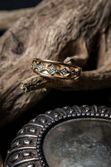 Golden ring on a wooden branch on a black background. Beautiful women's accessory