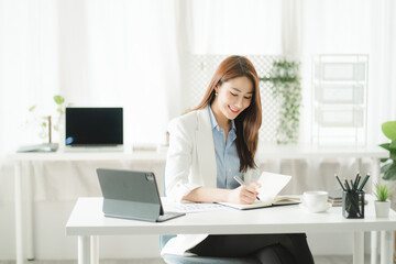 Portraits of beautiful smiling Asian women relax using laptop computer technology while sitting on their desks and using their creativity to work, work from home concept.