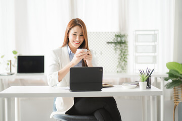 Portraits of beautiful smiling Asian women relax using laptop computer technology while sitting on their desks and using their creativity to work, work from home concept.