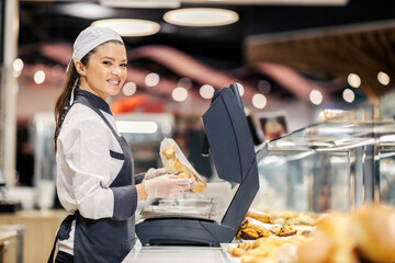 A happy bakery department saleswoman selling pastry at supermarket. - obrazy, fototapety, plakaty