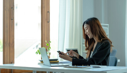 Asian businesswoman relax and enjoy playing mobile phone at office.