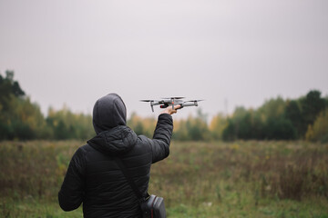 Man holding drone and remote control against field background