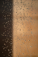 Abstract backgrond dropped water stop motion and dripping to the ground from Shower on blur orange brown background at outdoor light.