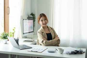 Obraz na płótnie Canvas Portrait of young beautiful asian businesswoman looking at camera and smile, arms crossed in modern office workplace
