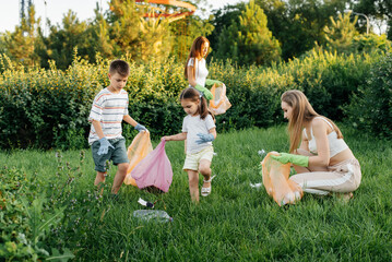 A group of adults and children together at sunset is engaged in garbage collection in the park....