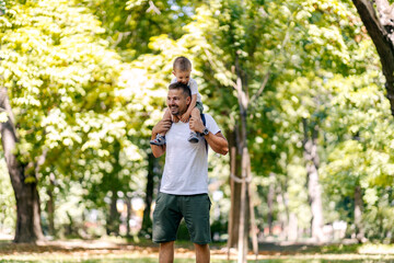 Naklejka premium Father and little boy having piggyback ride on pure air in nature.