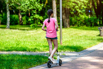 Girl rides an electric scooter in the summer Park