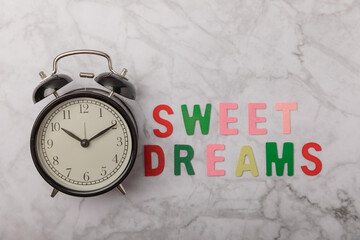 Sleeping eye mask, alarm clock and sweet dreams lettering on marble background. The concept of...