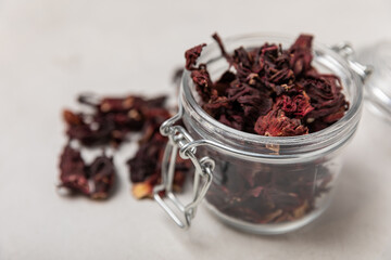 Hibiscus tea. Dried hibiscus leaves in a glass jar. Composition with organic, natural herbal tea on a light background. Vitamin tea for colds and flu. Copy space.
