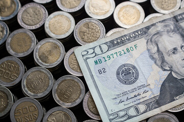 Twenty dollars over stacks of colombian coins of 500 and 1000, the Peso devaluation