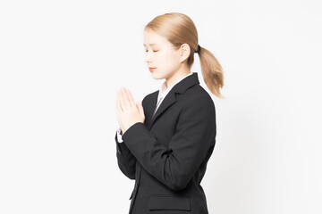 掌を合わせるジャケットを着た若い女性