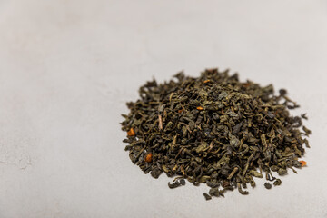 Green tea on a gray texture background. Dry green tea leaves. Fragrant tonic drink.Place to copy.