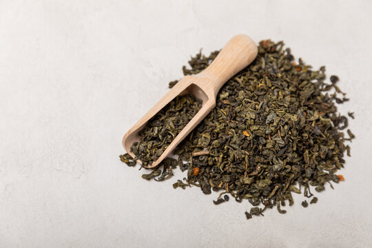 Green tea on a gray texture background. Dry green tea leaves. Fragrant tonic drink. Place to copy.