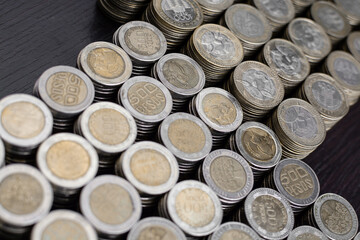 Pile of Colombian coins of 500 and 1000 denominations over wooden background. Ideal for economy,...