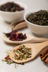 Various types of tea in wooden spoons on a light texture background. Tea mixture. Range. Black, green, herbal and hibiscus teas. Top view. Copy space.Various types of tea in wooden spoons on a light t