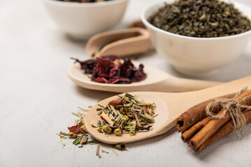 Various types of tea in wooden spoons on a light texture background. Tea mixture. Range. Black, green, herbal and hibiscus teas. Top view. Copy space.Various types of tea in wooden spoons on a light t